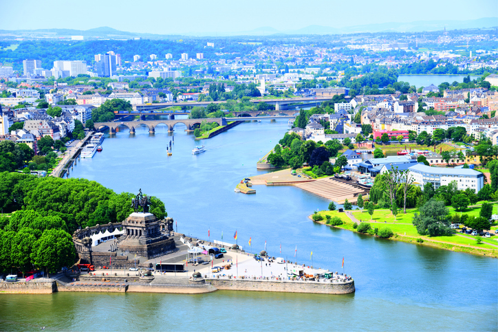 Blick aus großer Höhe auf den Zusammenfluss von Rhein und Mosel, die Stadt Koblenz und die umliegenden Brücken.