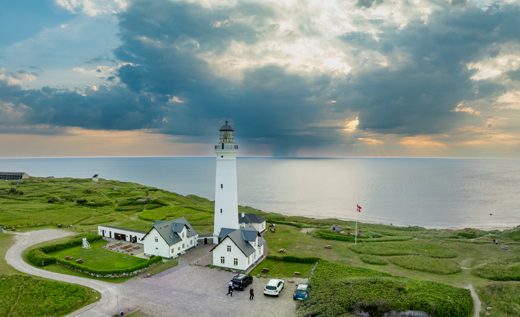 Luftaufnahme des strahlend weißen Leuchtturms Hirtshals Fyr und der umgebenden grünen Landschaft