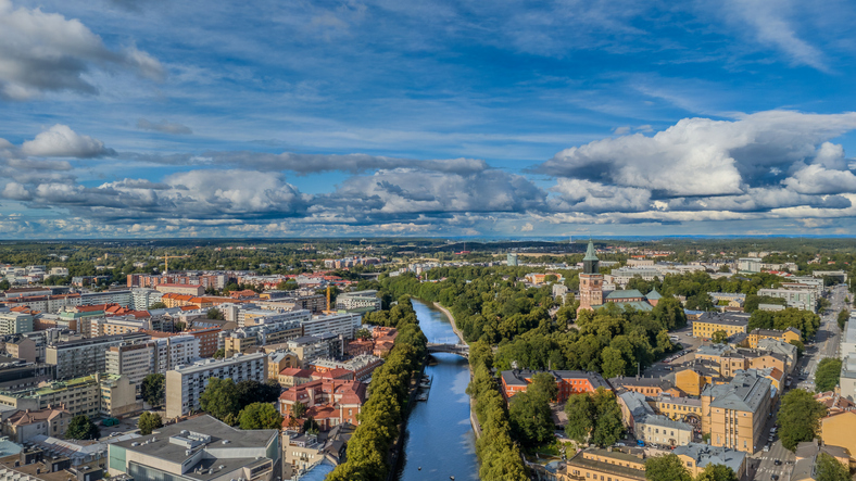 Panorama-Luftaufnahme der Stadt Turku mit dem geradlinigen Verlauf des Flusses und dem markanten Dom zwischen grünen Bäumen.