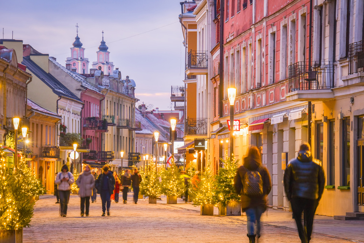 Menschen flanieren zur blauen Stunde durch eine festlich mit Lichterketten geschmückte historische Gasse in der Altstadt.