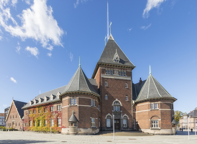 Das ehemalige Zollamt in Aarhus, ein markanter Backsteinbau mit Türmen und herbstlichem Efeu an der Fassade.