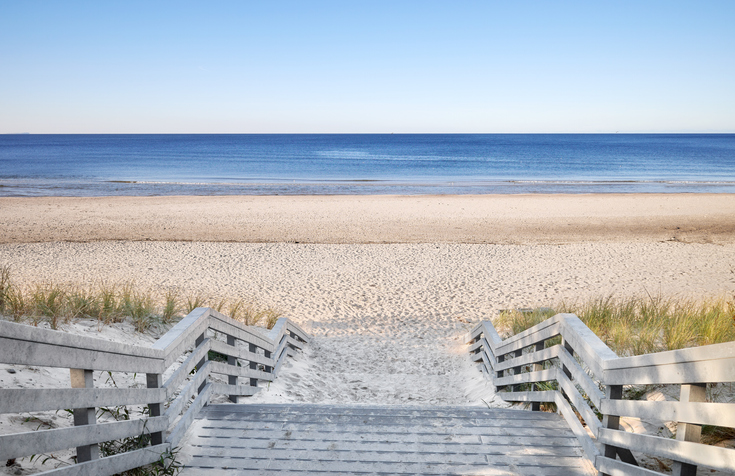 Ein hölzerner Treppenaufgang führt durch eine Dünenlandschaft hinunter zum breiten, menschenleeren Strand von Misdroy.