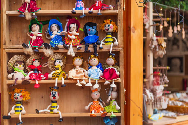 Ein hölzernes Regal gefüllt mit handgefertigten, bunt bemalten Holzpuppen an einem Marktstand in Košice.