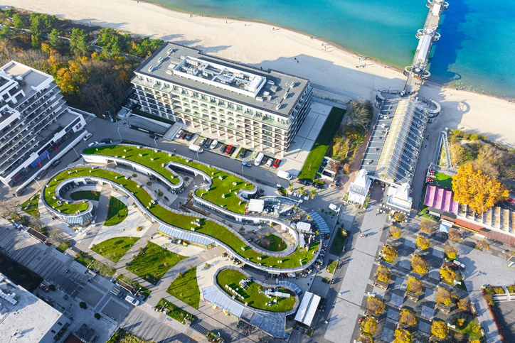 Luftaufnahme der Promenade in Misdroy mit grünen Dachterrassen, modernen Hotelgebäuden und dem angrenzenden Strand.