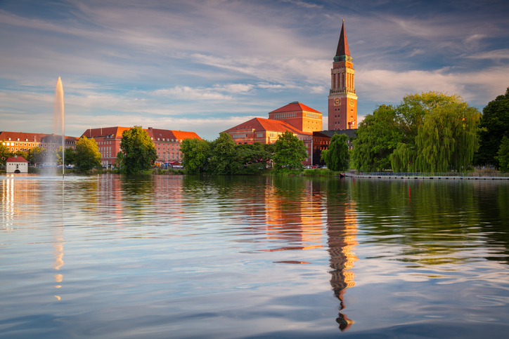 Das Rathaus von Kiel spiegelt sich bei stimmungsvoller Abendbeleuchtung im ruhigen Wasser.