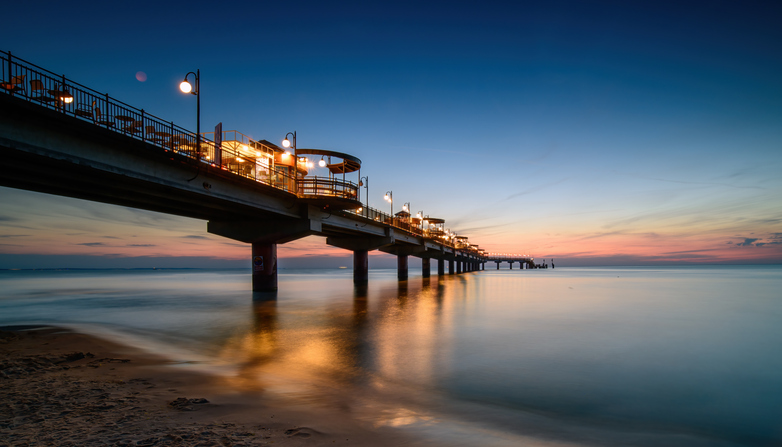Die beleuchtete Seebrücke von Misdroy bei Sonnenuntergang mit einer farbenprächtigen Lichtstimmung am Himmel.