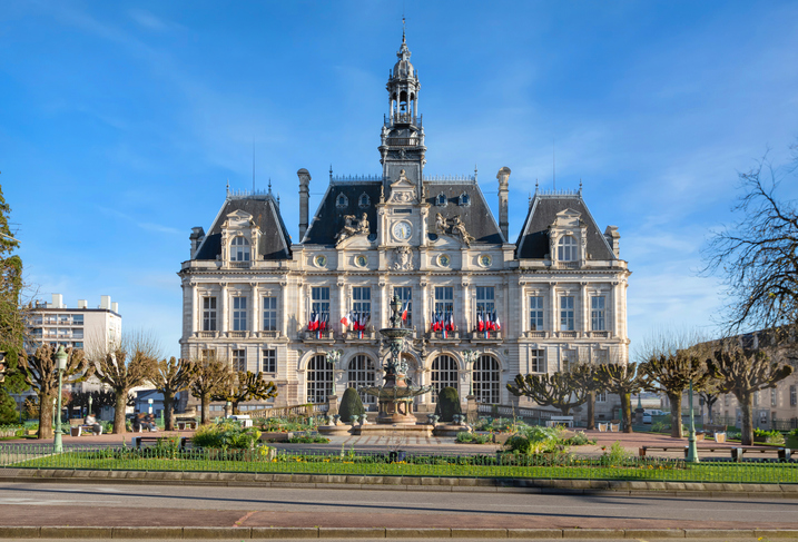 Das Rathaus von Limoges mit Brunnen, Türmen und gepflegter Gartenanlage bei klarem Himmel.