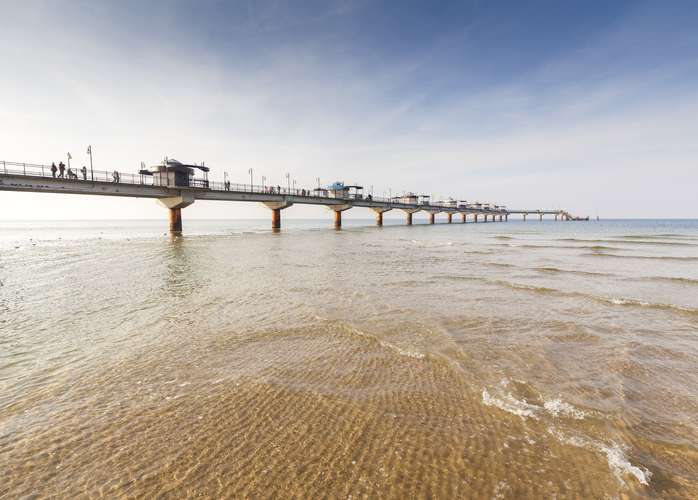 Eine lange, moderne Seebrücke in Misdroy, die weit in das ruhige, flache Ostseewasser hineinreicht.
