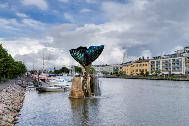 Eine moderne, bunte Skulptur in Form einer Walflosse steht direkt im Wasser des Aura-Flusses in Turku.