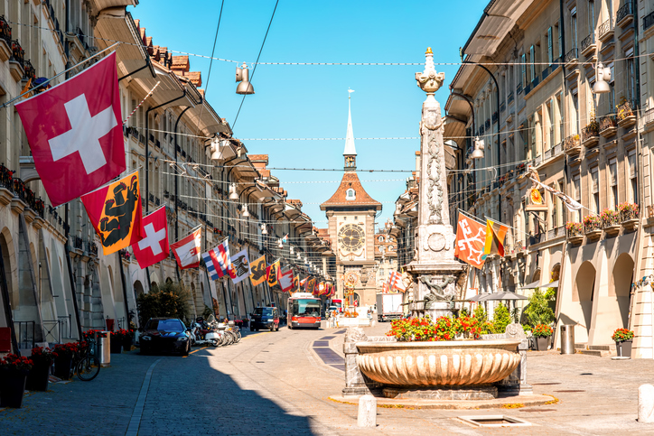 Straßenszene in der Kramgasse mit Schweizer Fahnen und dem Uhrturm Zytglogge in Bern