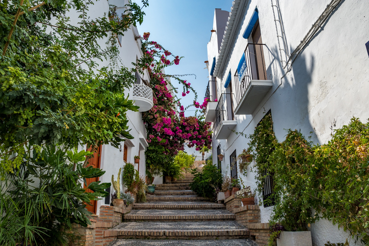 Eine Treppe in der Altstadt von Salobreña, üppig geschmückt mit pinkfarbenen Bougainvillea und grünen Pflanzen.