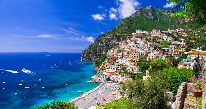 Ein weiter Blick über die bunte Stadt Positano, die sich an die steilen Klippen der Amalfiküste schmiegt, mit einem belebten Strand und dem tiefblauen Meer.
