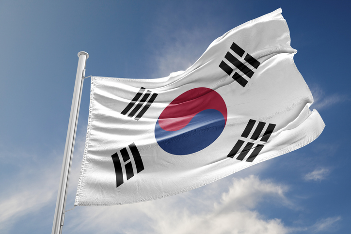 Die südkoreanische Flagge (Taegeukgi) weht stolz vor einem strahlend blauen Himmel an einem Mast.