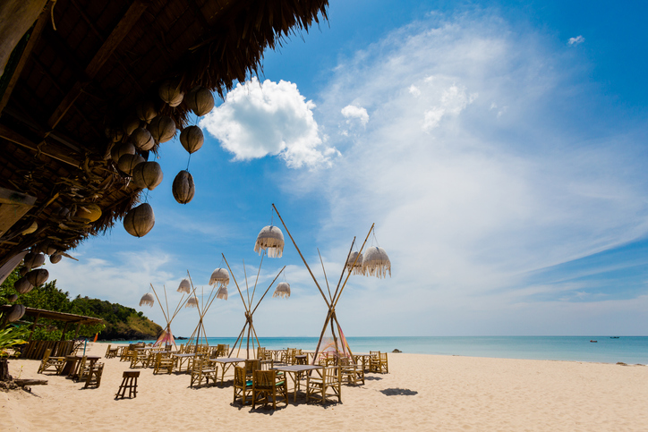 Ein Restaurant mit Kokosnuss-Dekorationen direkt am Strand mit Blick auf das offene Meer.