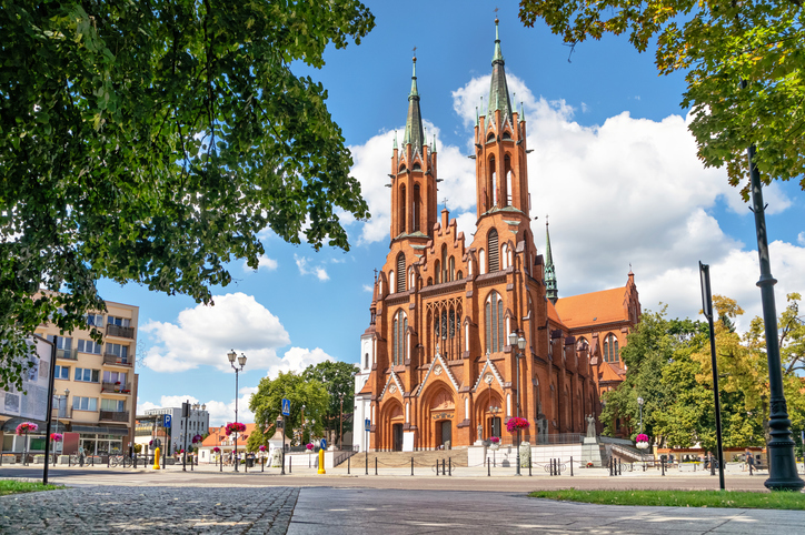 Die beeindruckende, rote Backstein-Kathedrale von Białystok mit ihren zwei markanten Türmen unter einem blauen Himmel.