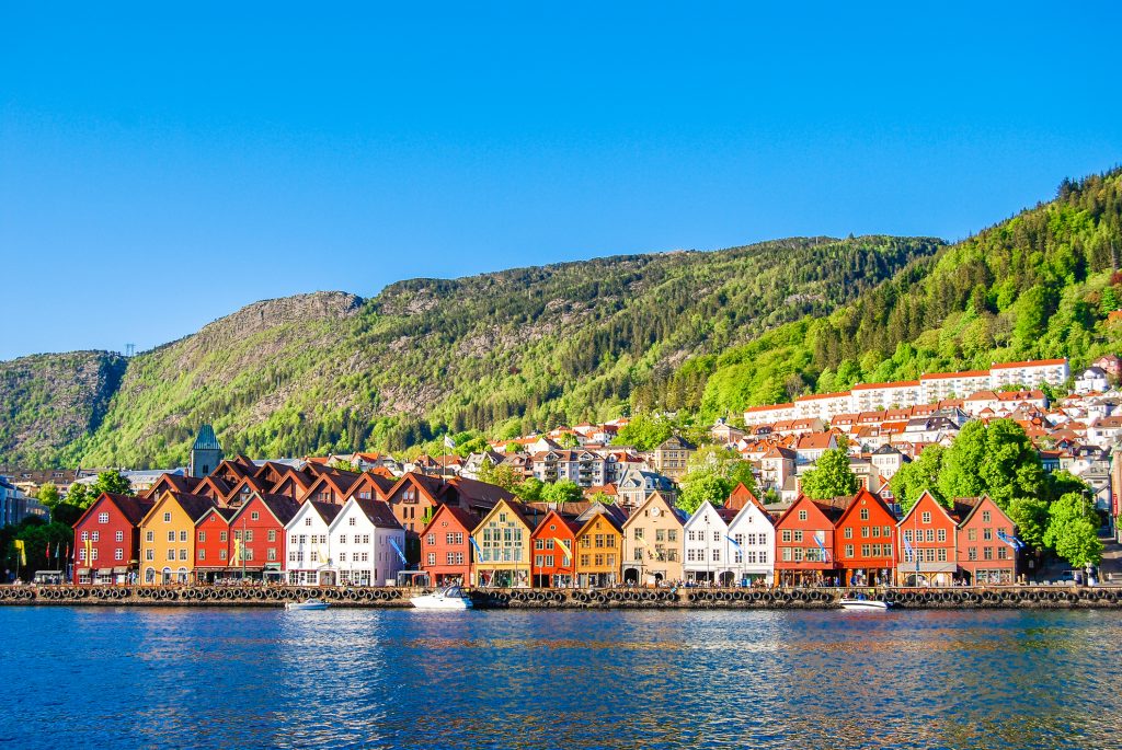 Die charakteristischen roten und braunen Speicherhäuser spiegeln sich im ruhigen Wasser des Nidelva-Flusses.