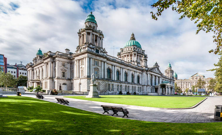 Ein Blick auf das imposante Rathaus von Belfast mit seiner großen Grünfläche und den markanten Kuppeln.