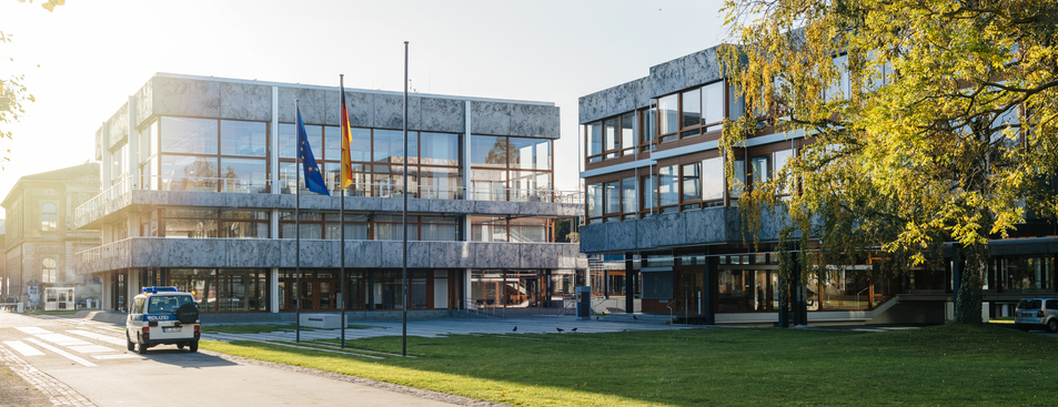 Ein modernes Bürogebäude aus Glas und Beton in Karlsruhe, davor ein Polizeifahrzeug.