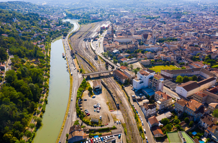 Eine Luftaufnahme, die den Fluss Garonne neben den Bahngleisen und dem Stadtgebiet von Agen zeigt.