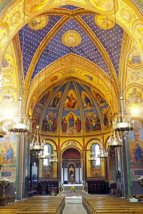 Blick in das farbenfrohe Innere einer Kirche in Agen mit beeindruckenden Deckengemälden und Verzierungen.