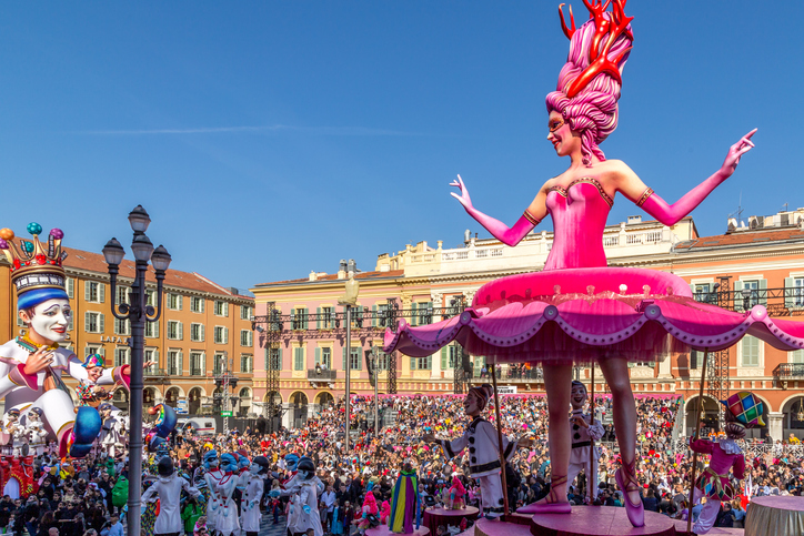 Bunte Figuren, Kostüme und Menschenmengen füllen den Place Masséna beim Karneval in Nizza.
