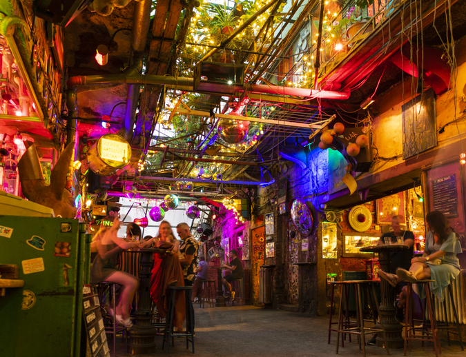 Eine bunt beleuchtete Bar mit Tischen, Deko und gemütlicher Atmosphäre in Budapest.