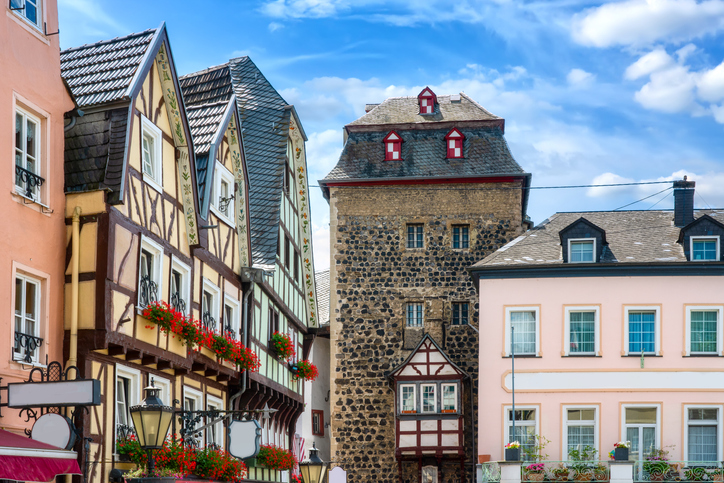 Ein Ensemble aus malerischen Fachwerkhäusern und einem alten Steinturm an einem sonnigen Tag unter blauem Himmel.