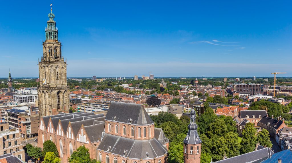 Der hohe, historische Martiniturm erhebt sich über dem Stadtzentrum und den umliegenden Gebäuden unter einem klaren blauen Himmel.