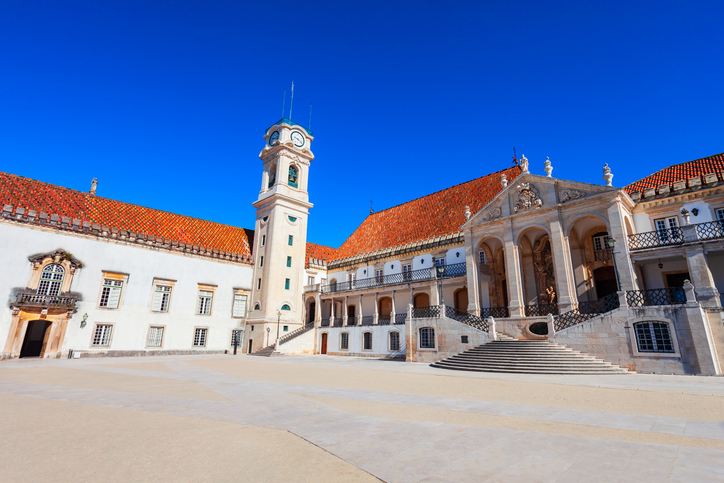 Der berühmte Glockenturm und die historischen Fassaden der Universität von Coimbra an einem sonnigen Tag.