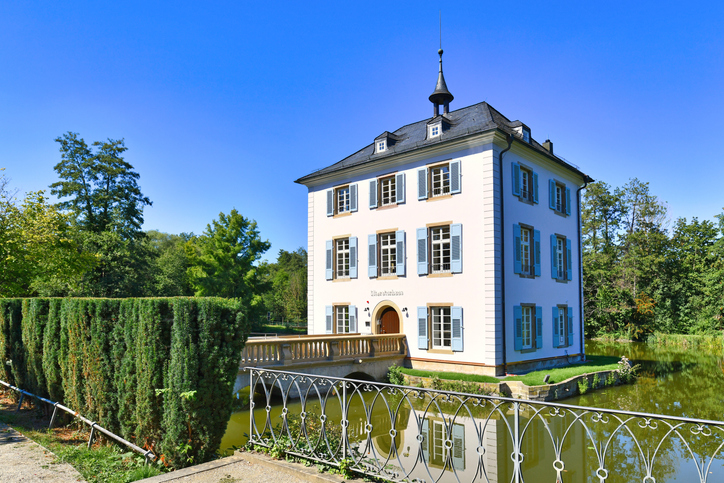 Das kleine, elegante Wasserschloss mit seinen hellen Wänden und blauen Fensterläden steht in einer grünen Parkanlage bei Heilbronn.