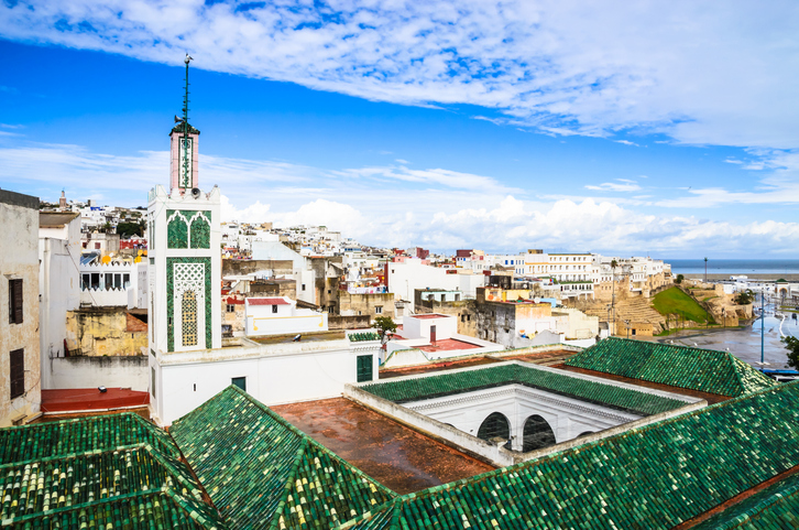 Weiße Häuser, grüne Dächer und ein Minarett prägen den Blick über die Medina von Tanger.
