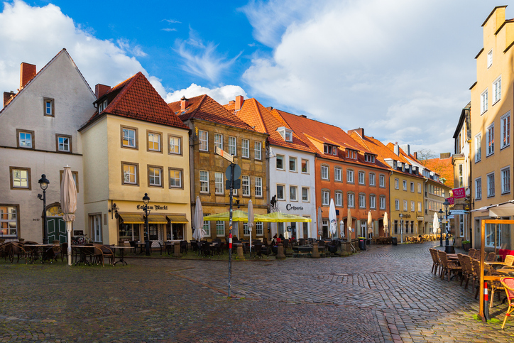 Eine Reihe farbenfroher historischer Giebelhäuser säumt den gepflasterten Marktplatz in der Altstadt von Osnabrück.