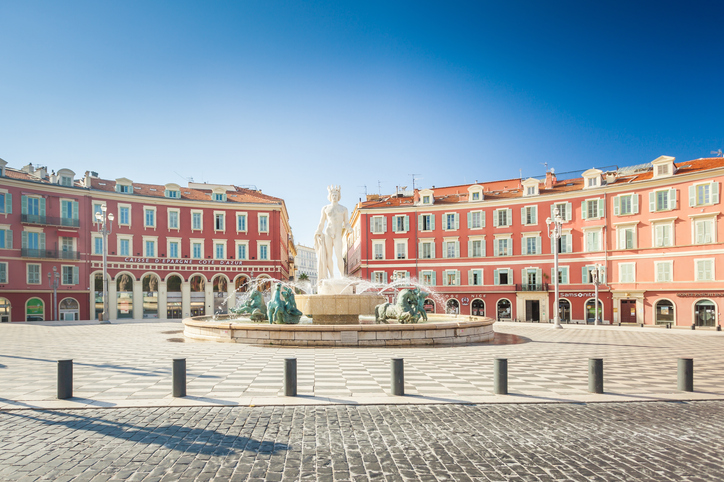 Der Place Masséna in Nizza mit Brunnen, roten Fassaden und hellem Stadtplatz.