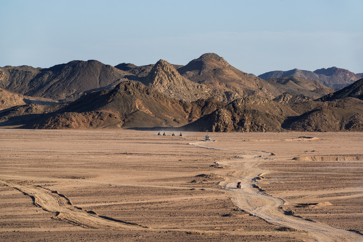 Eine Gruppe auf Quads fährt durch die weite, trockene Wüstenlandschaft im Hinterland von Hurghada.