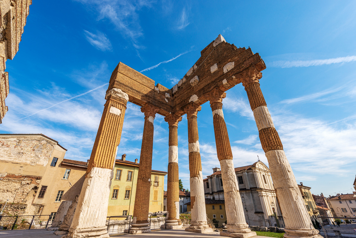 Die beeindruckenden, freistehenden römischen Säulen des Capitolium-Tempels ragen vor einem strahlend blauen Himmel empor.