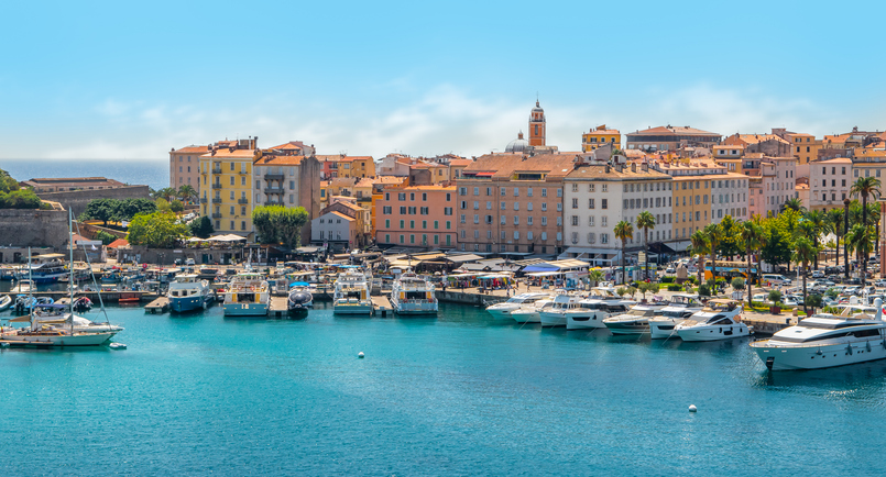Blick auf den belebten Hafen von Bastia mit zahlreichen Segelbooten und Yachten vor einer historischen Stadtkulisse.