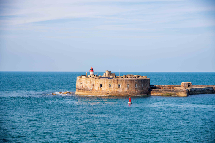 Ein altes, rundes Steinfort im Meer vor Cherbourg mit einem kleinen Leuchtturm.