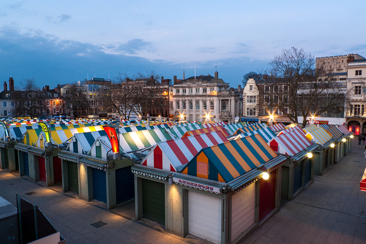 Die farbenfrohen Marktstände auf dem Markt in Norwich stehen bei einsetzender Abenddämmerung in einer ordentlichen Reihe.