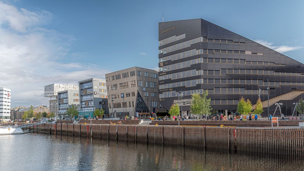 Das moderne, dunkel gestaltete Powerhouse-Gebäude steht direkt an einer hölzernen Hafenpromenade.