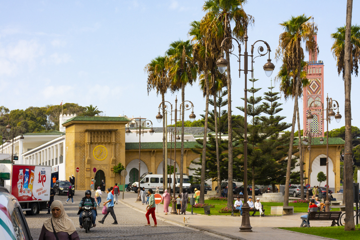 Ein belebter Platz in Tanger mit Moschee, Palmen und marokkanischer Stadtatmosphäre.