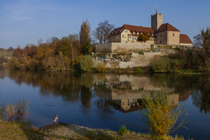 Ein malerisches Wasserschloss spiegelt sich bei ruhigem Wetter in einem Teich nahe der Umgebung von Heilbronn wider.