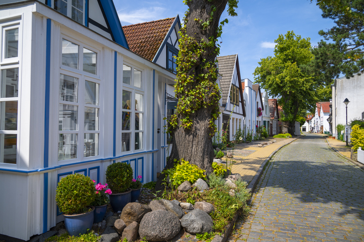 Malerische, traditionelle weiße Fachwerkhäuser mit blauen Details in einer ruhigen Seitenstraße von Warnemünde.
