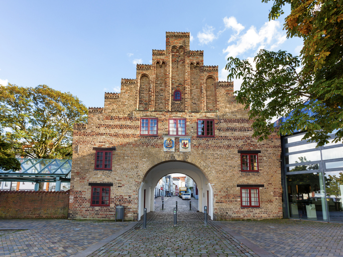 Das alte Nordertor aus rotem Backstein mit seinem markanten Treppengiebel steht als ehemaliger Eingang zur Stadt unter einem sonnigen Himmel.