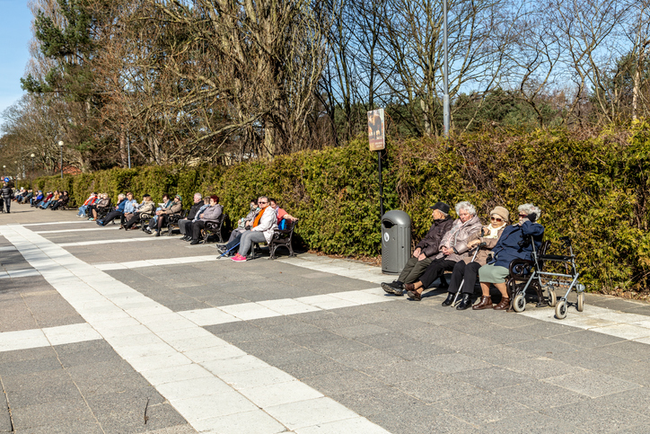 Ältere Menschen sitzen auf Bänken entlang der Promenade in Ahlbeck und genießen die Sonne.