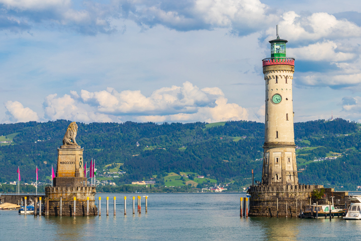 Der imposante Leuchtturm steht neben der markanten Löwenstatue, die den Eingang zum Hafen bewacht, im Hintergrund sind Berge zu sehen