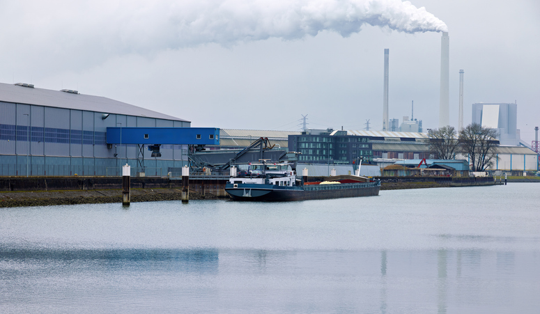 Ein Frachtschiff liegt an einem Kai im Karlsruher Hafen, im Hintergrund sind Industrieanlagen zu sehen.