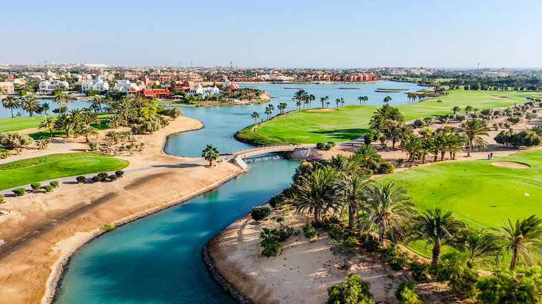 Ein grüner Golfplatz, der von Wasserwegen durchzogen ist und in Hurghada direkt am Meer liegt.