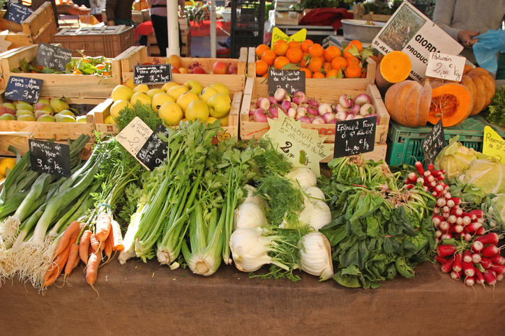 Frisches Gemüse, Kräuter und Kürbis liegen auf einem Marktstand in Nizza.