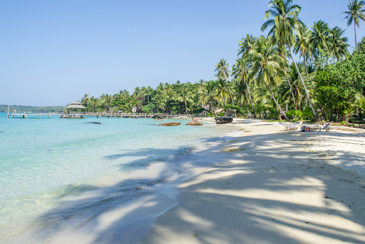 Ein weißer Sandstrand mit hohen Palmen und bequemen Sonnenliegen lädt zum Verweilen ein.