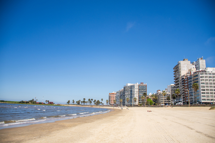 Ein weitläufiger Sandstrand entlang der Küstenstraße von Montevideo mit modernen Wohngebäuden.